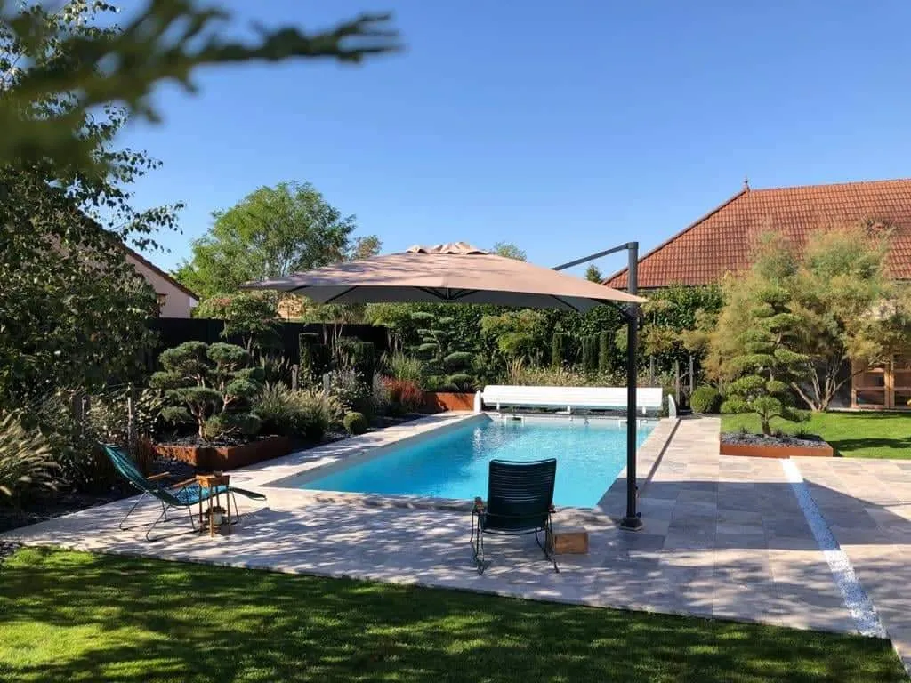 Piscine, pergola et pelouse entourées d'arbres taillés dans un jardin paysager – Hortiplan Paysagiste