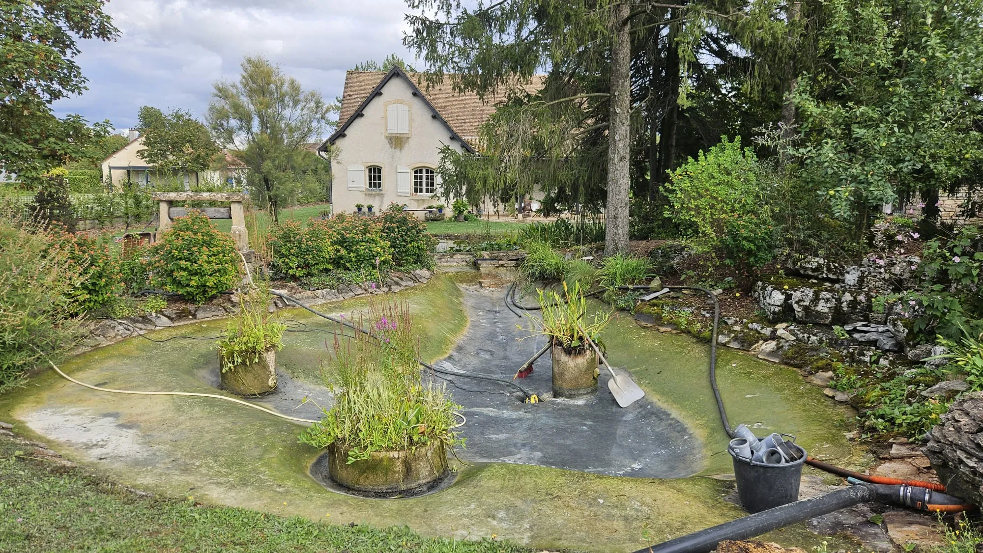 Grand bassin en cours de plantation devant une maison, chantier de création de bassin – Hortiplan Paysagiste