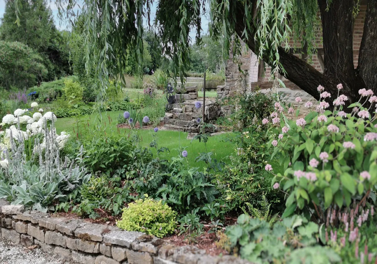 Massifs de vivaces fleuries, pelouse et muret en pierre sèche dans un jardin d'agrément – Hortiplan Paysagiste