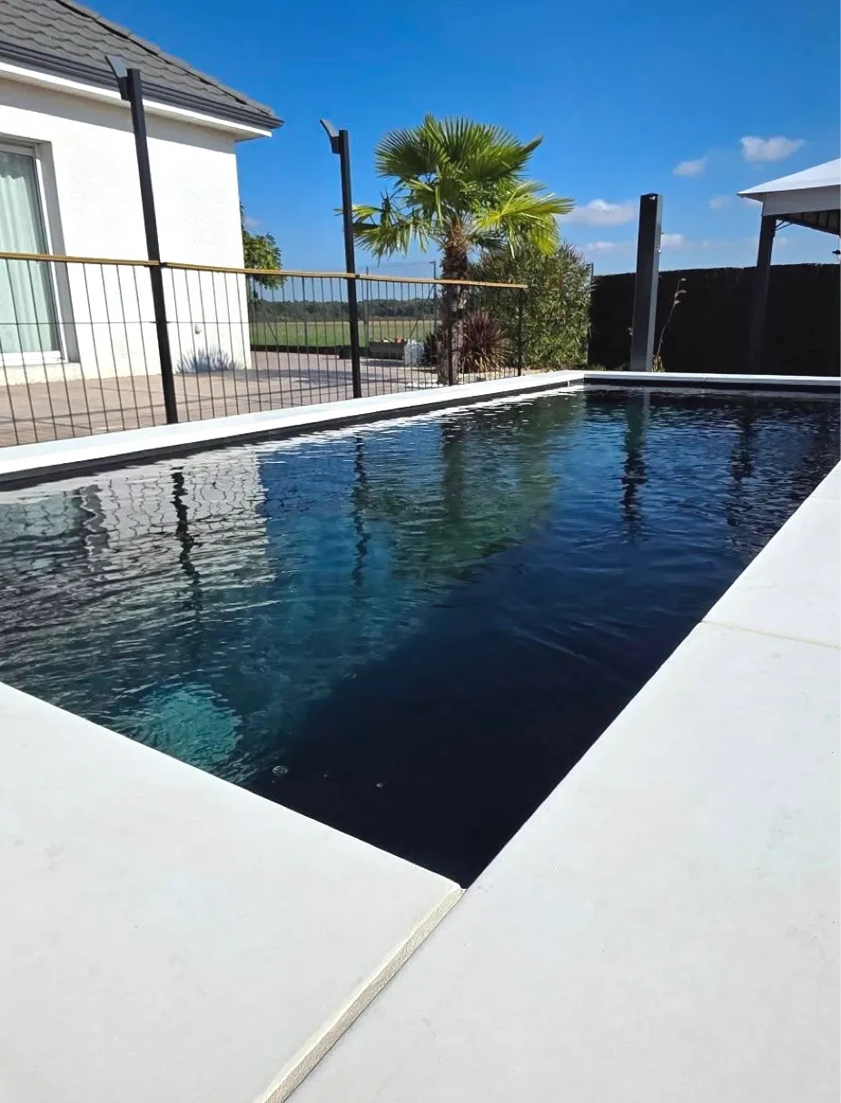 Piscine rectangulaire à l'eau sombre bordée de margelles blanches, aménagement d'abord de piscine Chagny 71150 – Hortiplan Paysagiste