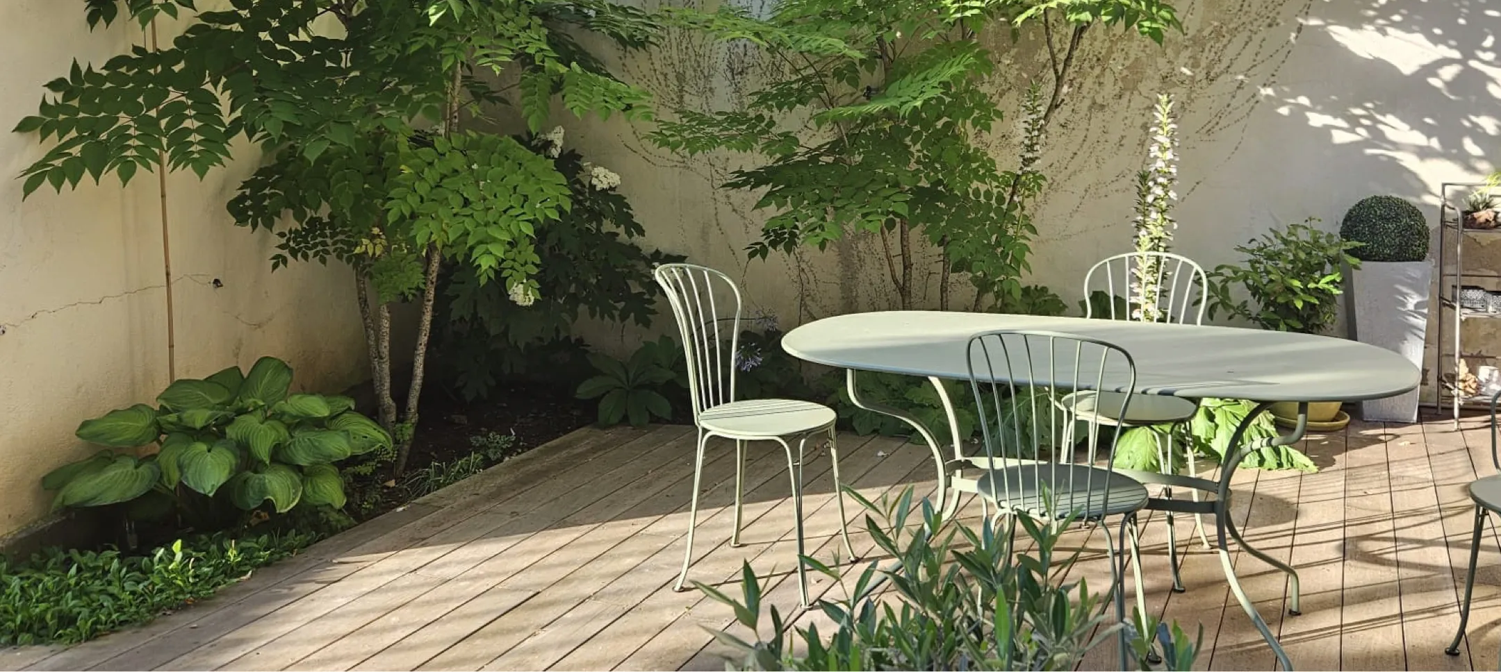 Terrasse pavée meublée d'un salon de jardin en métal bordée d'un massif de plantes d'ombre – Hortiplan Paysagiste